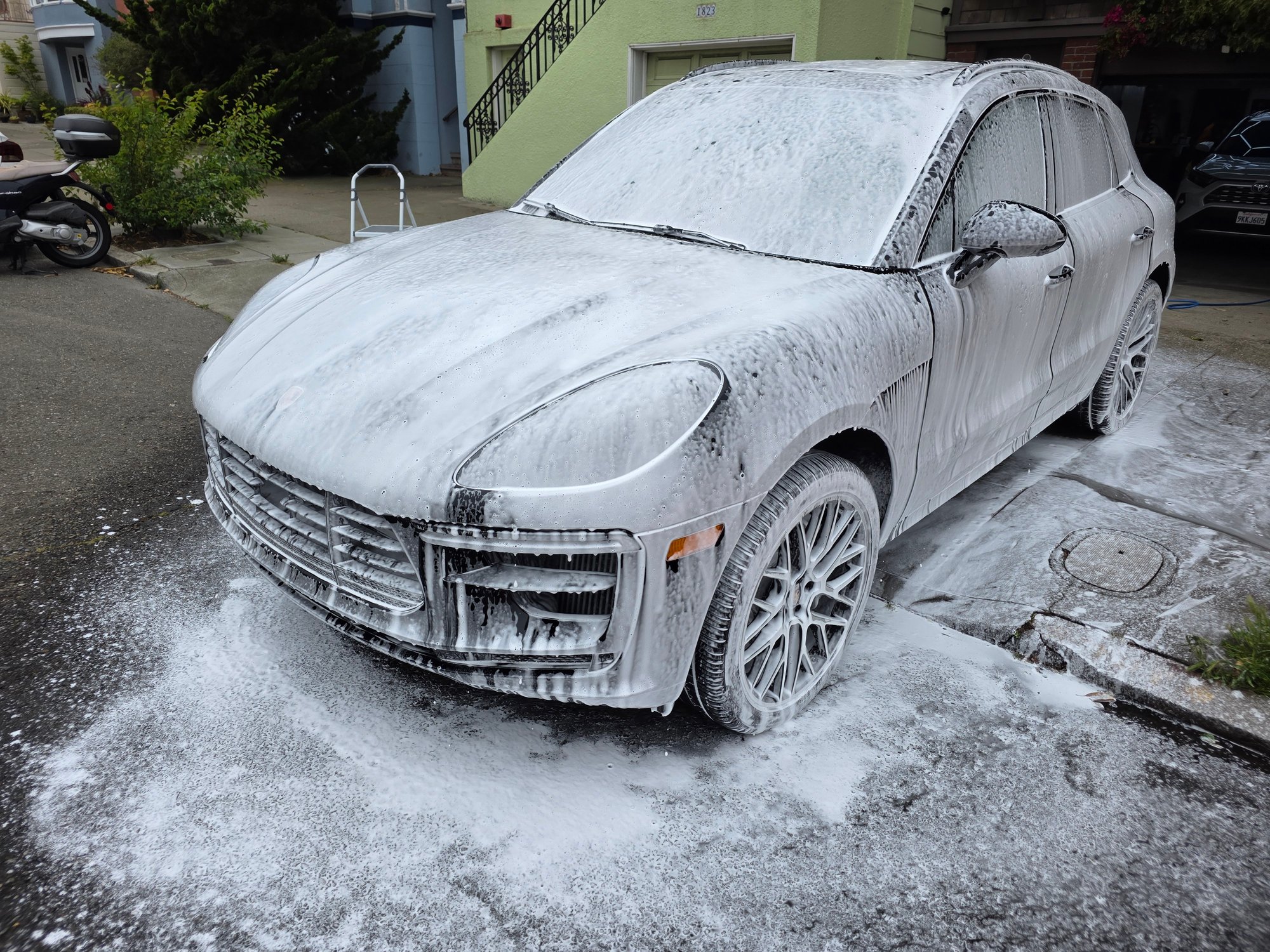 Luxury SUV covered in snow foam during mobile detailing.
