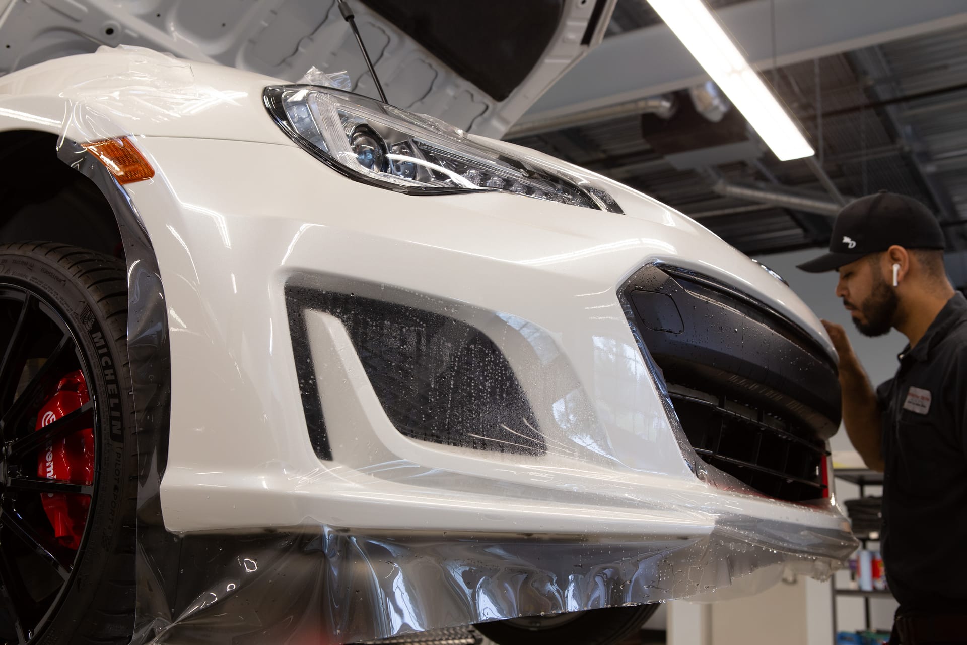 White Porsche 911 bumper getting paint protection film installed.