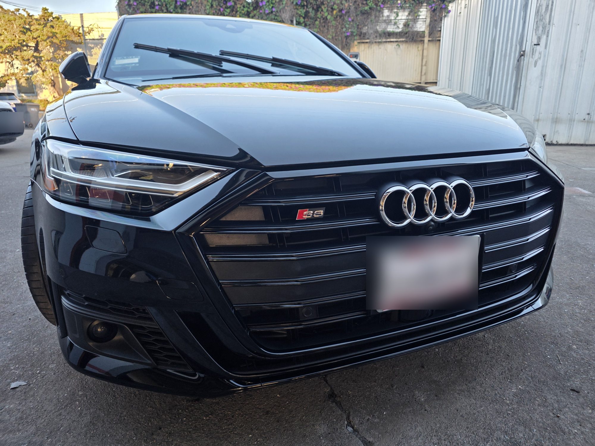 Straight-on front view of a ceramic-coated black Audi S8, grille and headlights reflecting the evening light.