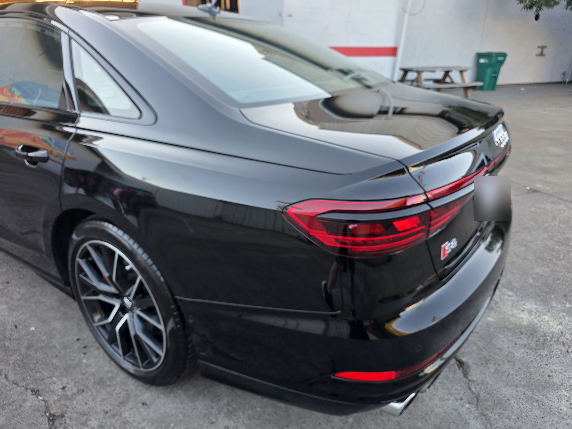 Rear three-quarter view of a black Audi S8 after ceramic coating, quarter panel and tail light in the last of the sun.