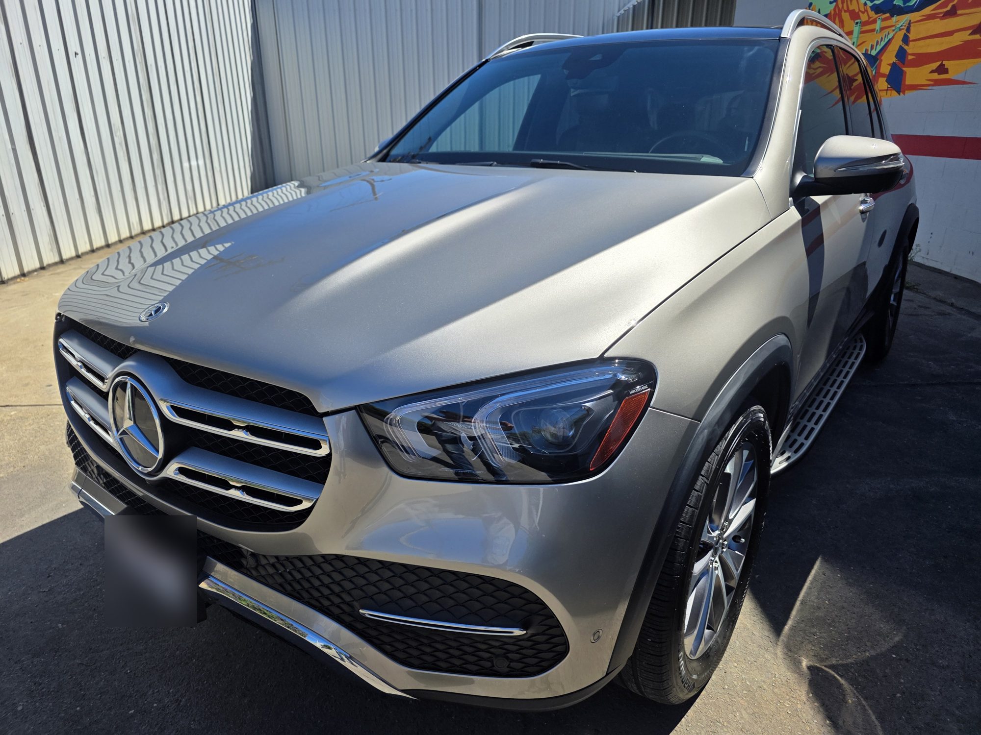 Close front view of a ceramic-coated silver Mercedes-Benz GLE, grille and hood in direct sun.