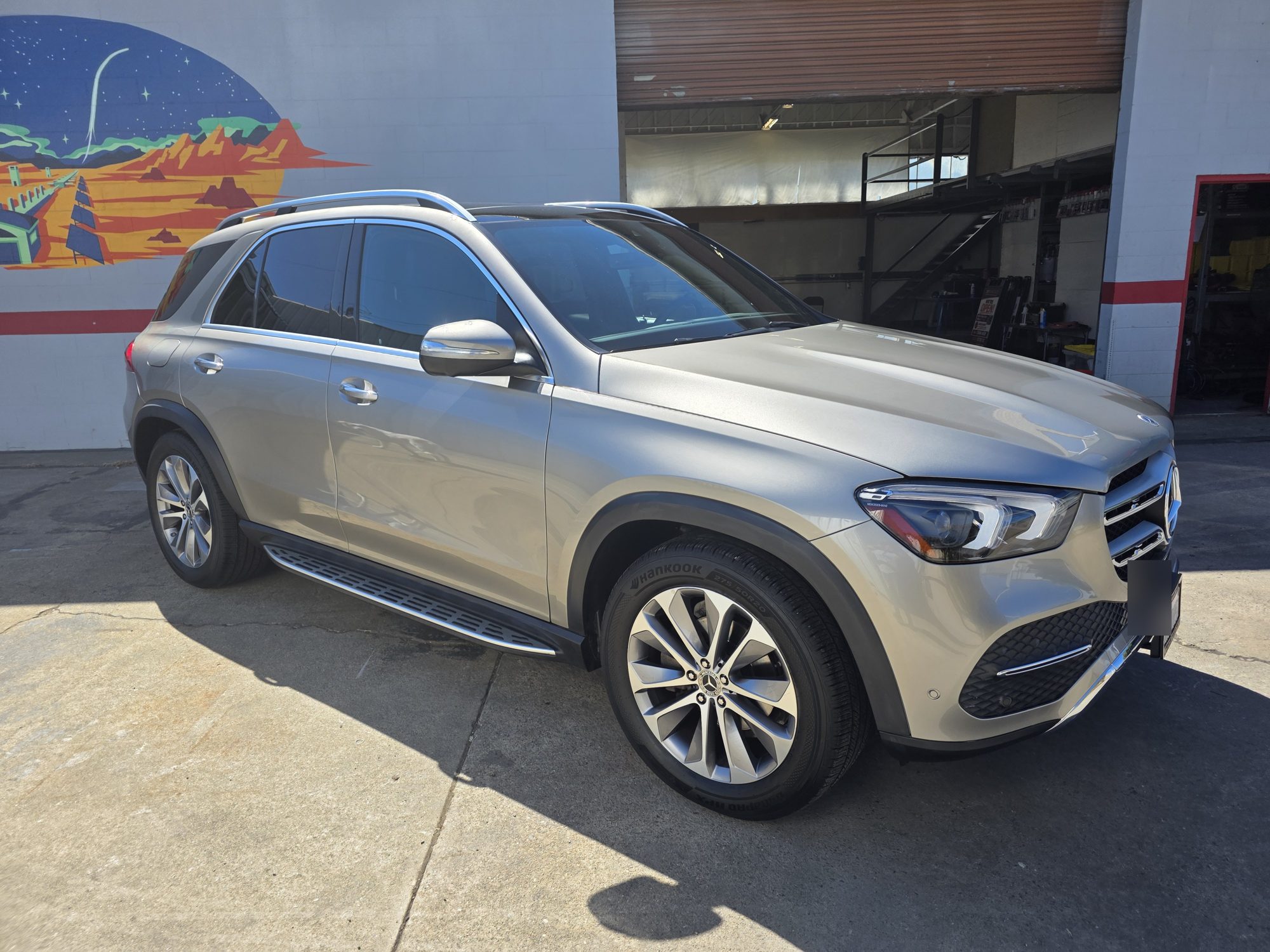 Side profile of a silver Mercedes-Benz GLE after ceramic coating, parked by the mural at the Innovo shop in Oakland.