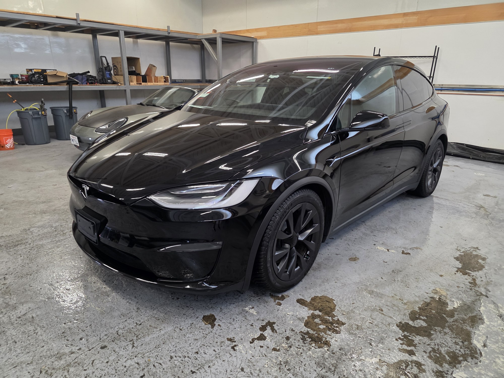 Black Tesla Model X in the Innovo shop before the colour-change film install, front three-quarter view.