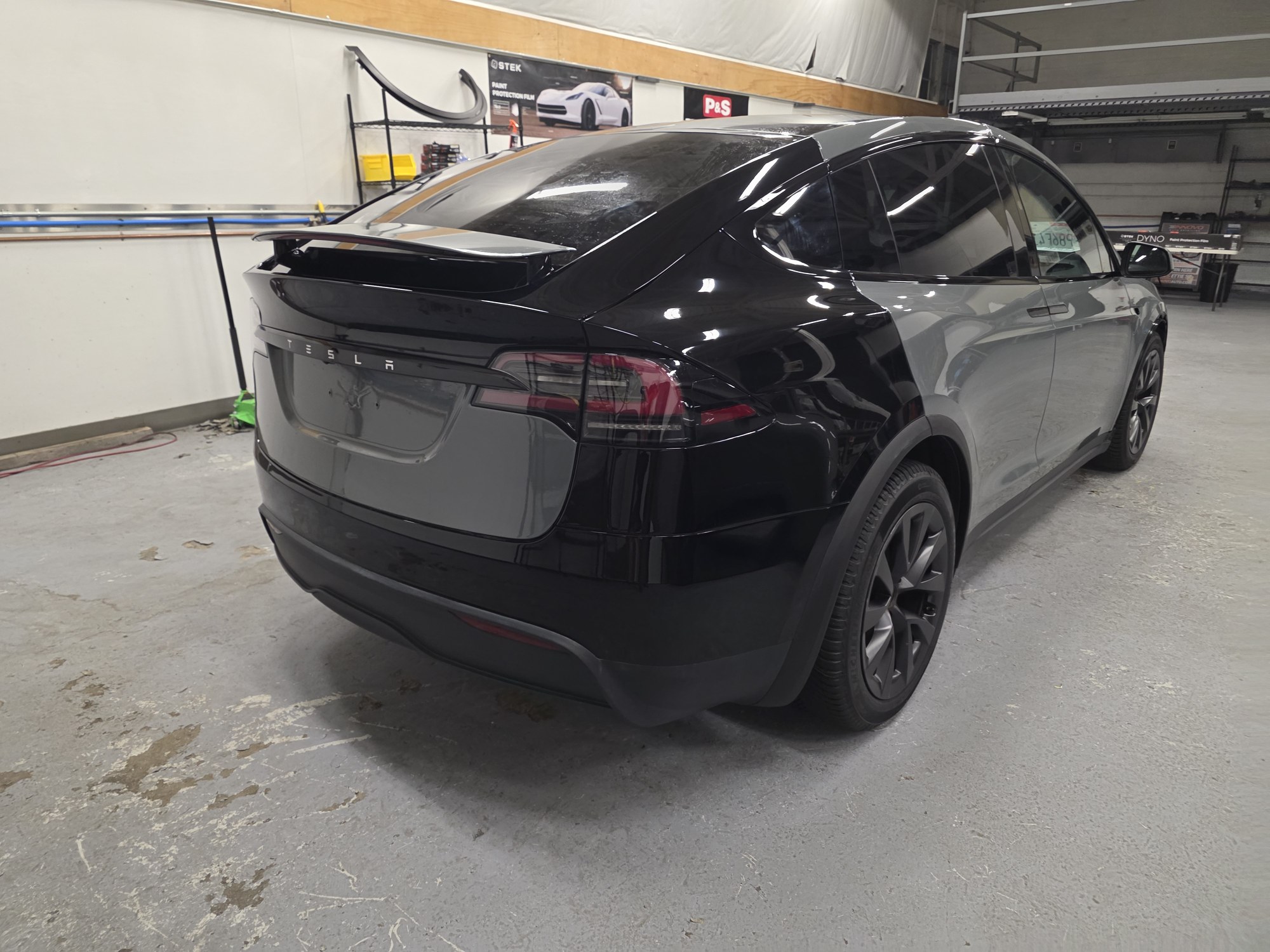 Rear three-quarter view of the black Tesla Model X in the shop before the grey film went on.