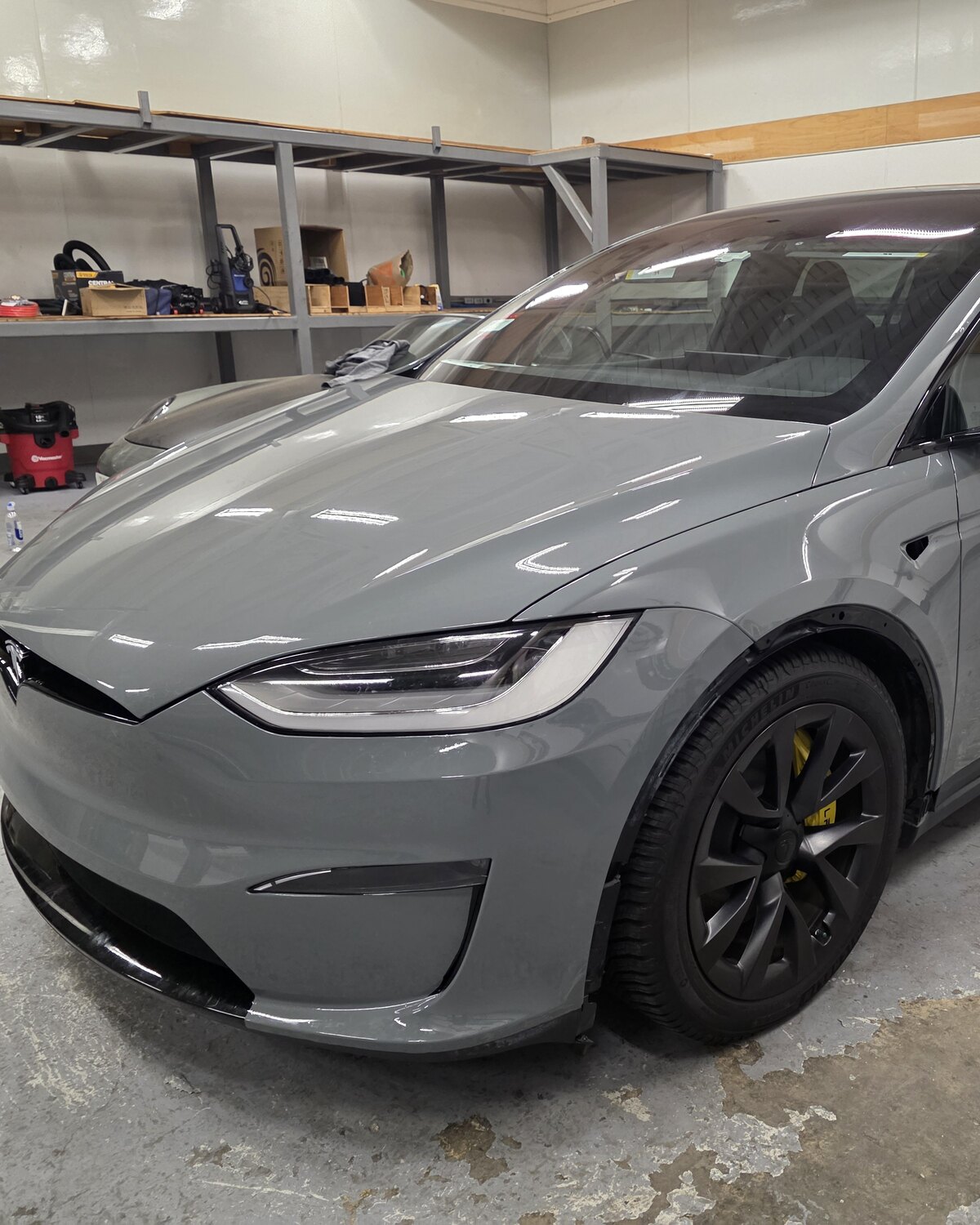 Tesla Model X in satin grey colour-change paint protection film in the Innovo shop in Oakland, front three-quarter view.