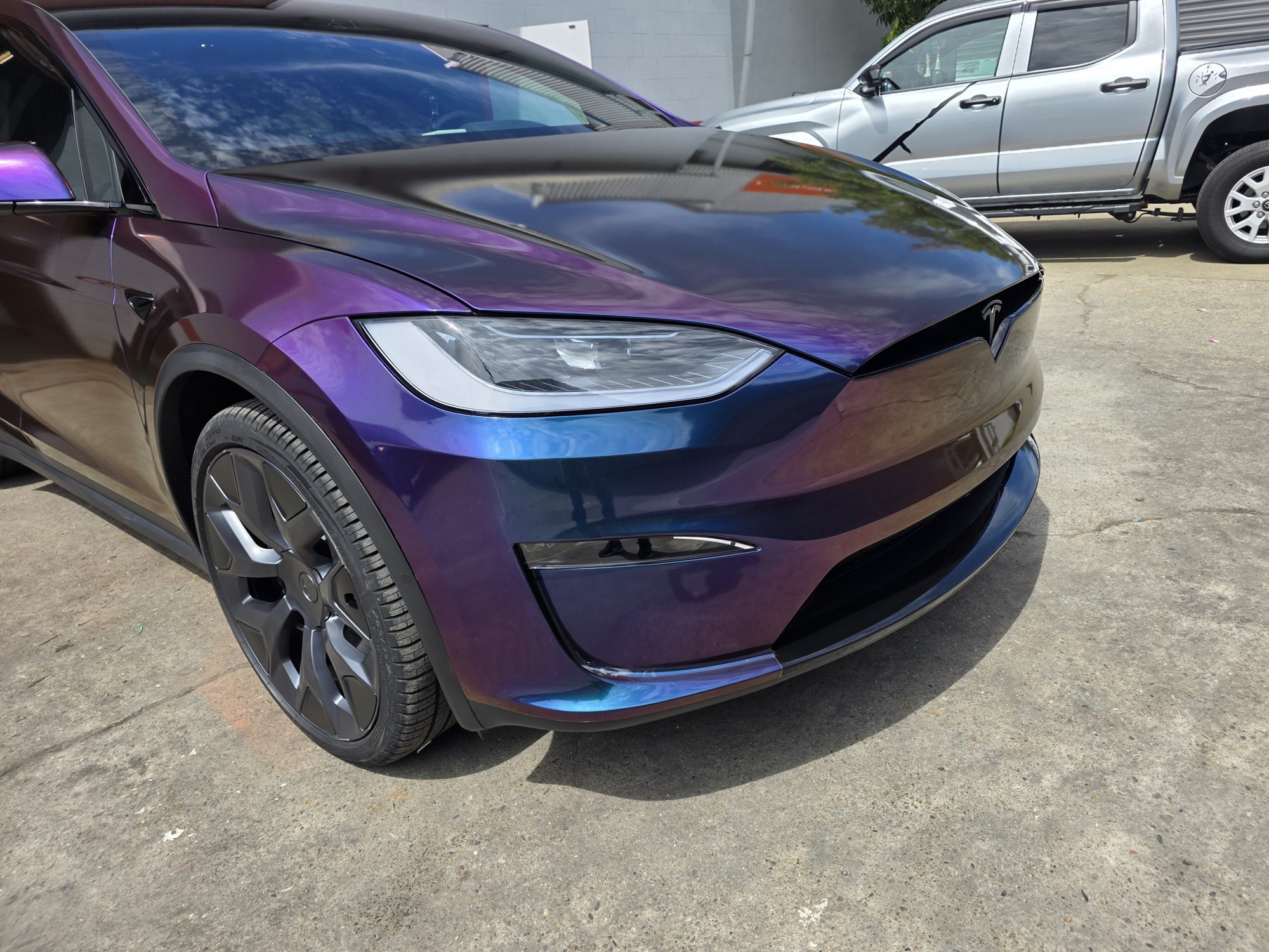 Headlight and fender detail on a colour-flip wrapped Tesla Model X after a full-body clear PPF install, film edges wrapped out of sight.
