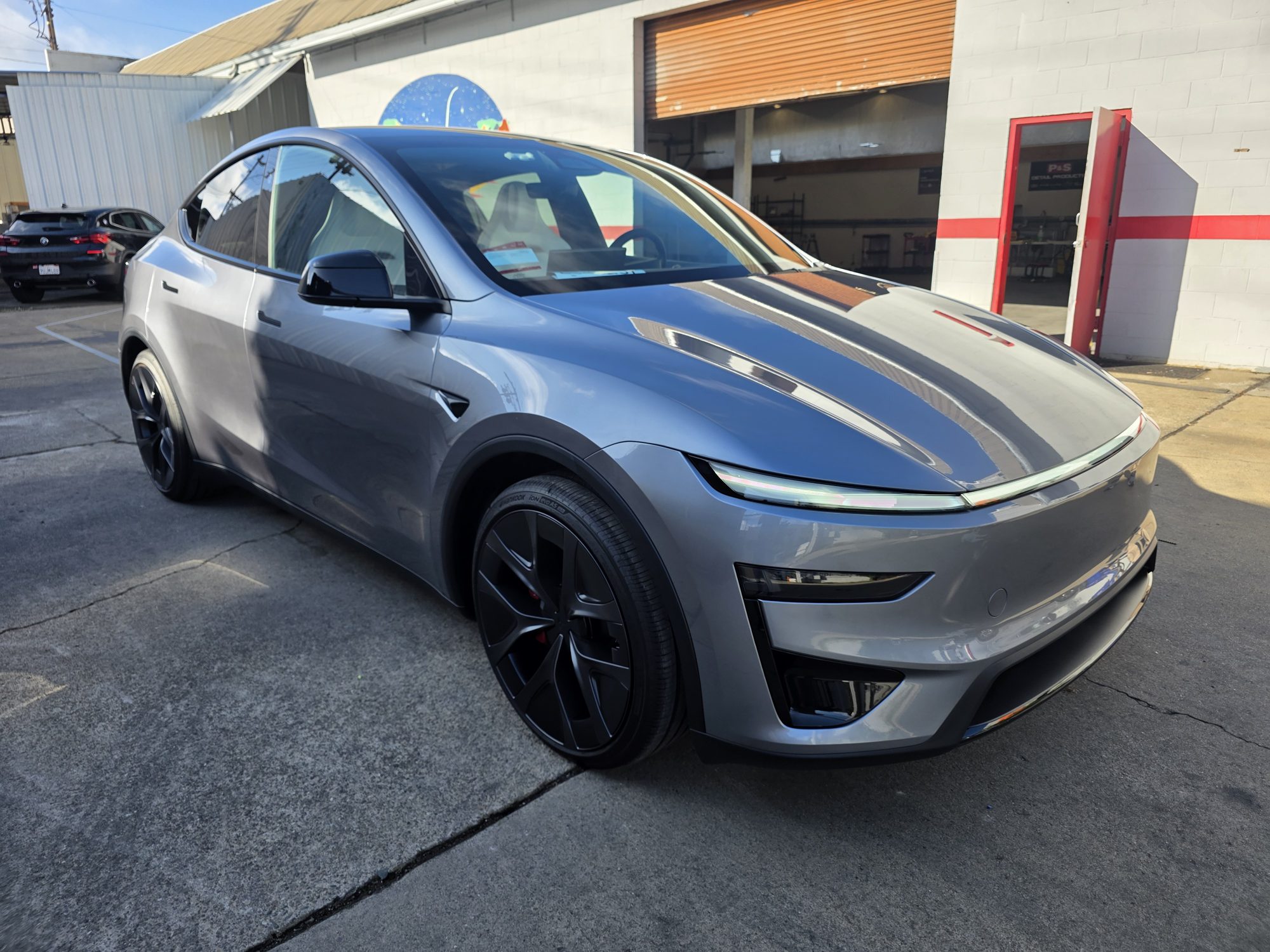 Grey 2026 Tesla Model Y after a full front-end STEK DYNOshield paint protection film install, front three-quarter view outside the Innovo shop.