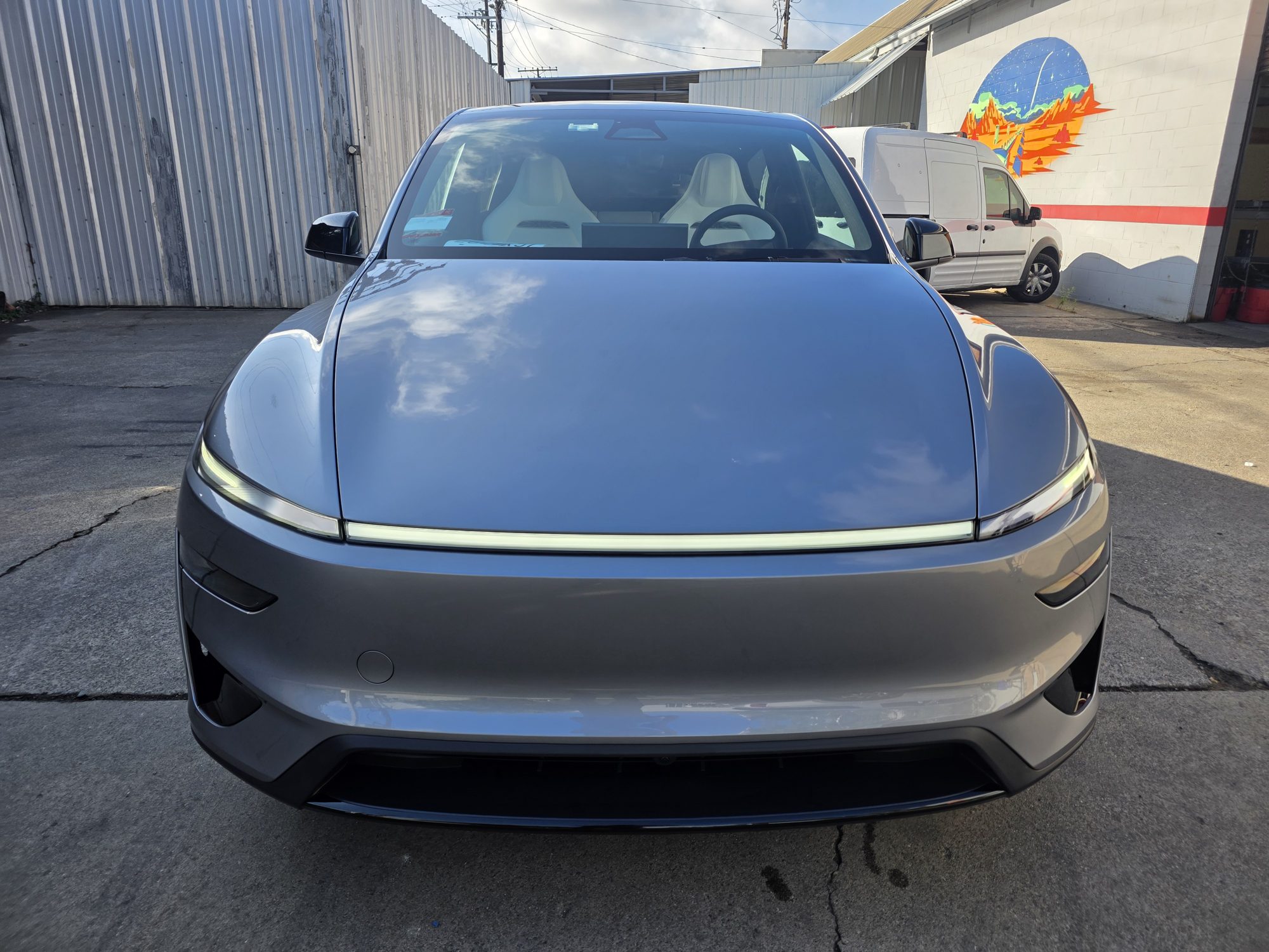 Straight-on front view of a Tesla Model Y with clear paint protection film on the hood, bumper and fenders; the film is invisible at this distance.