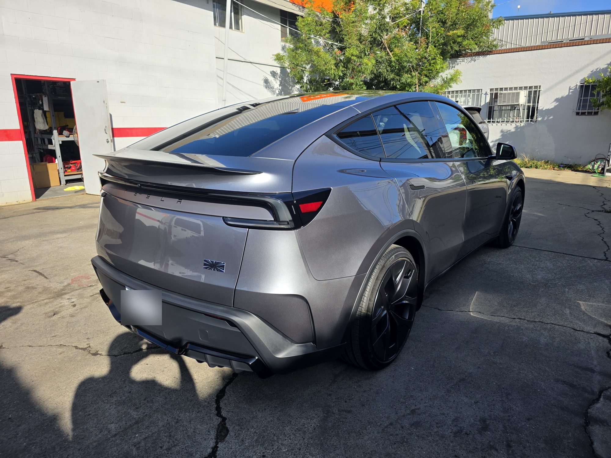 Tesla Model Y rear three-quarter view at the Innovo shop door after STEK DYNOshield front PPF and a P&S STOUT ceramic coating.