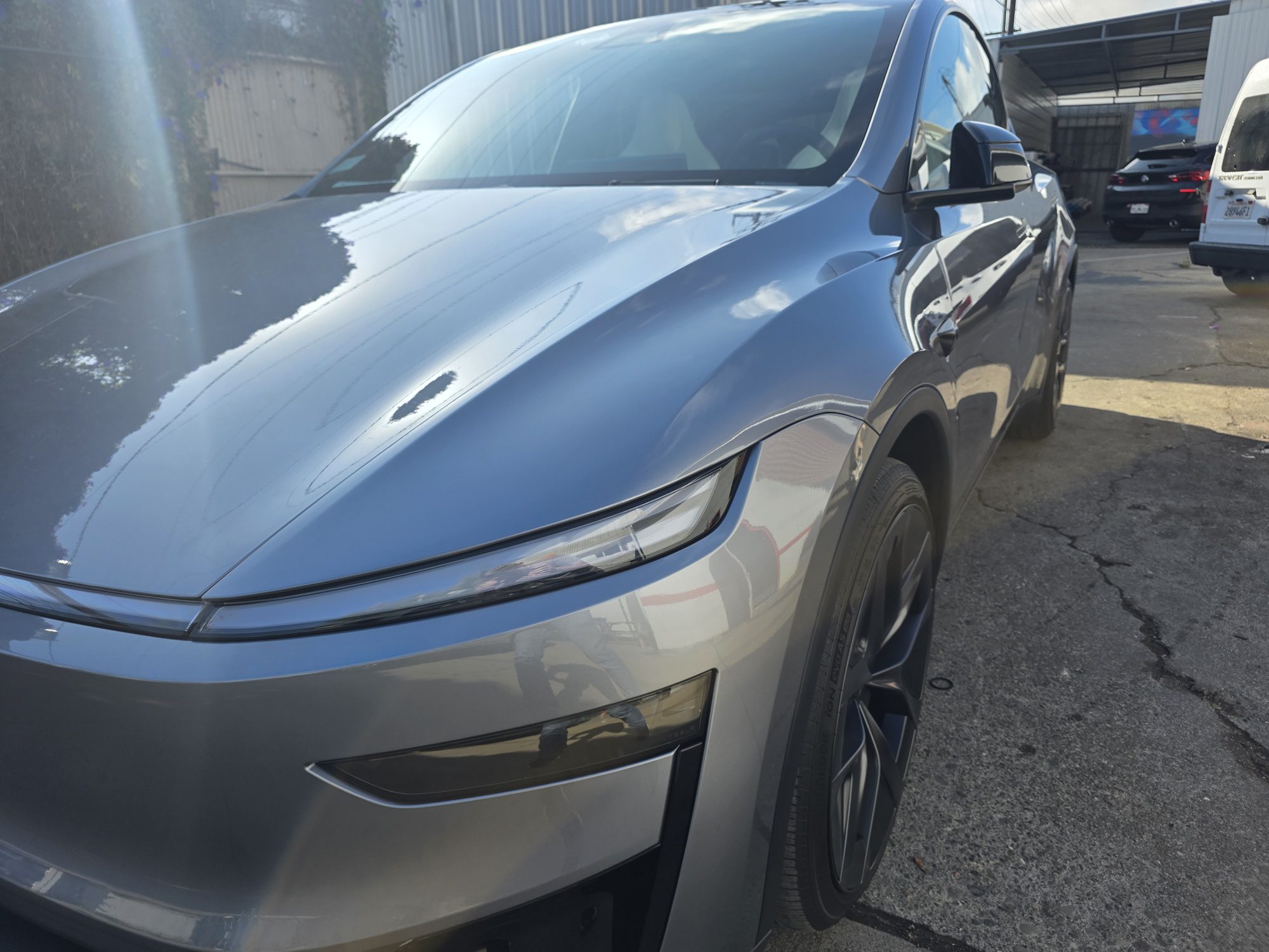 Close detail of the hood-to-fender seam on a Tesla Model Y with clear paint protection film, the film edge hard to find under the ceramic coating.