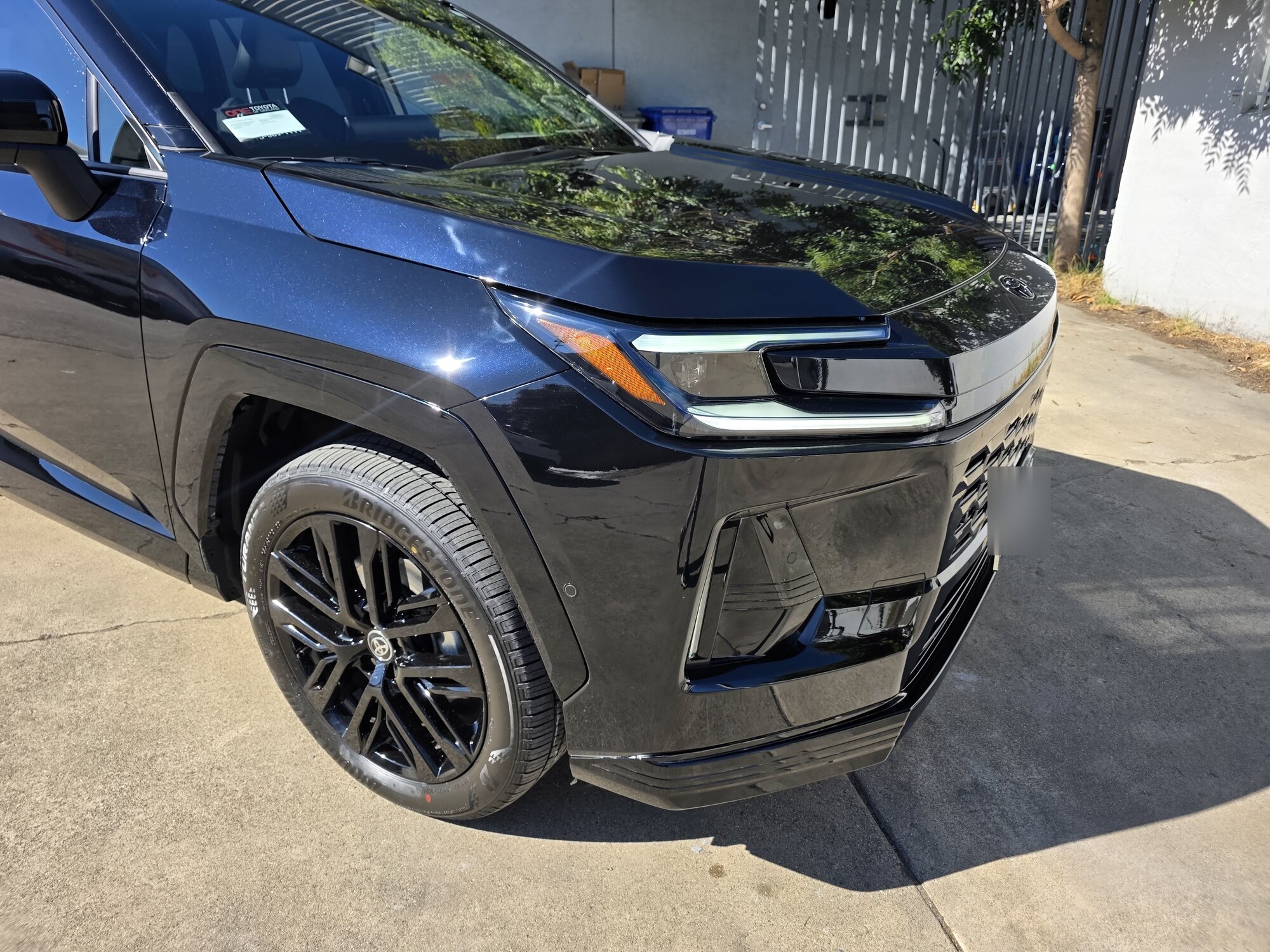 Dark blue 2026 Toyota RAV4 after a full front STEK paint protection film install and ceramic coating, front three-quarter view in the sun outside the Innovo shop in Oakland.