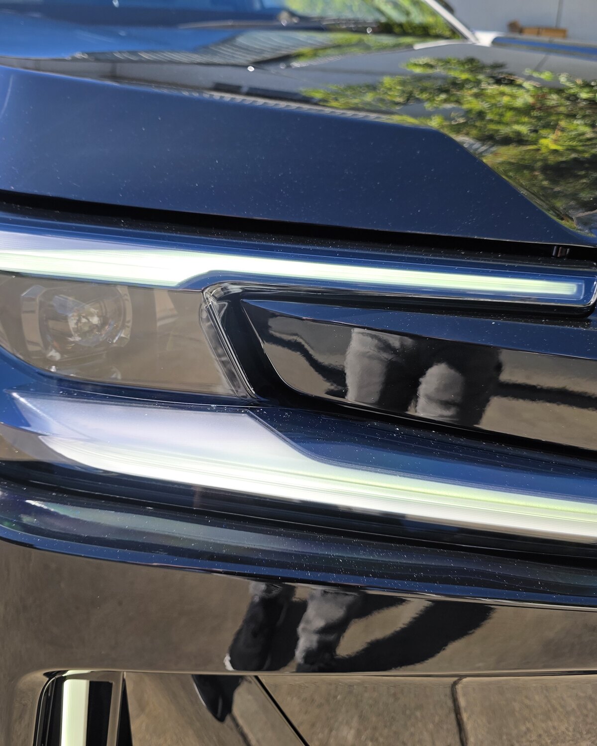 Close-up of the hood-to-headlight seam on a dark blue 2026 Toyota RAV4 with clear paint protection film, the film edge tucked along the lens.