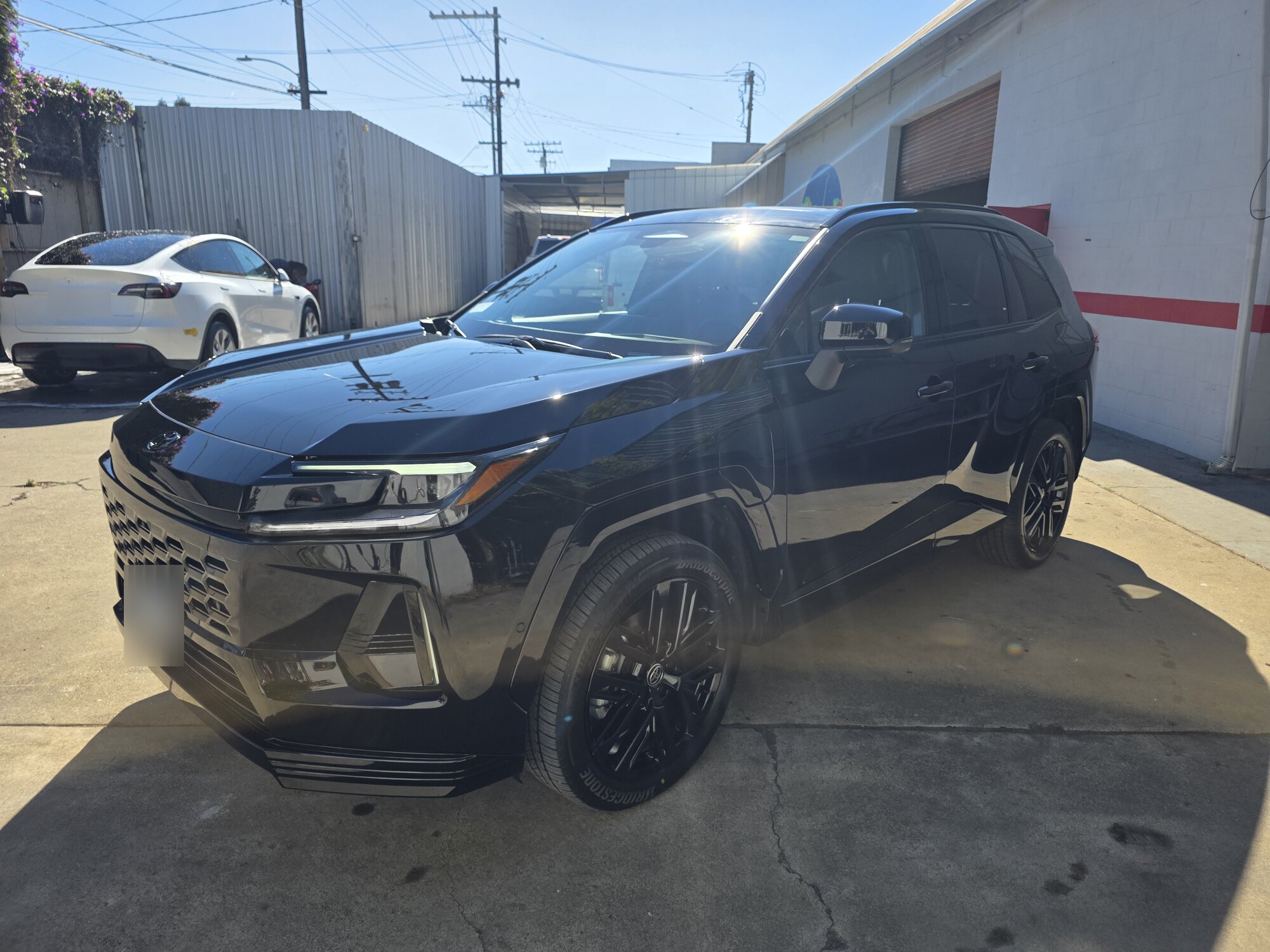 Dark blue 2026 Toyota RAV4 in direct sun after full front paint protection film and a full-vehicle ceramic coating, wide front three-quarter view at the Innovo shop in Oakland.