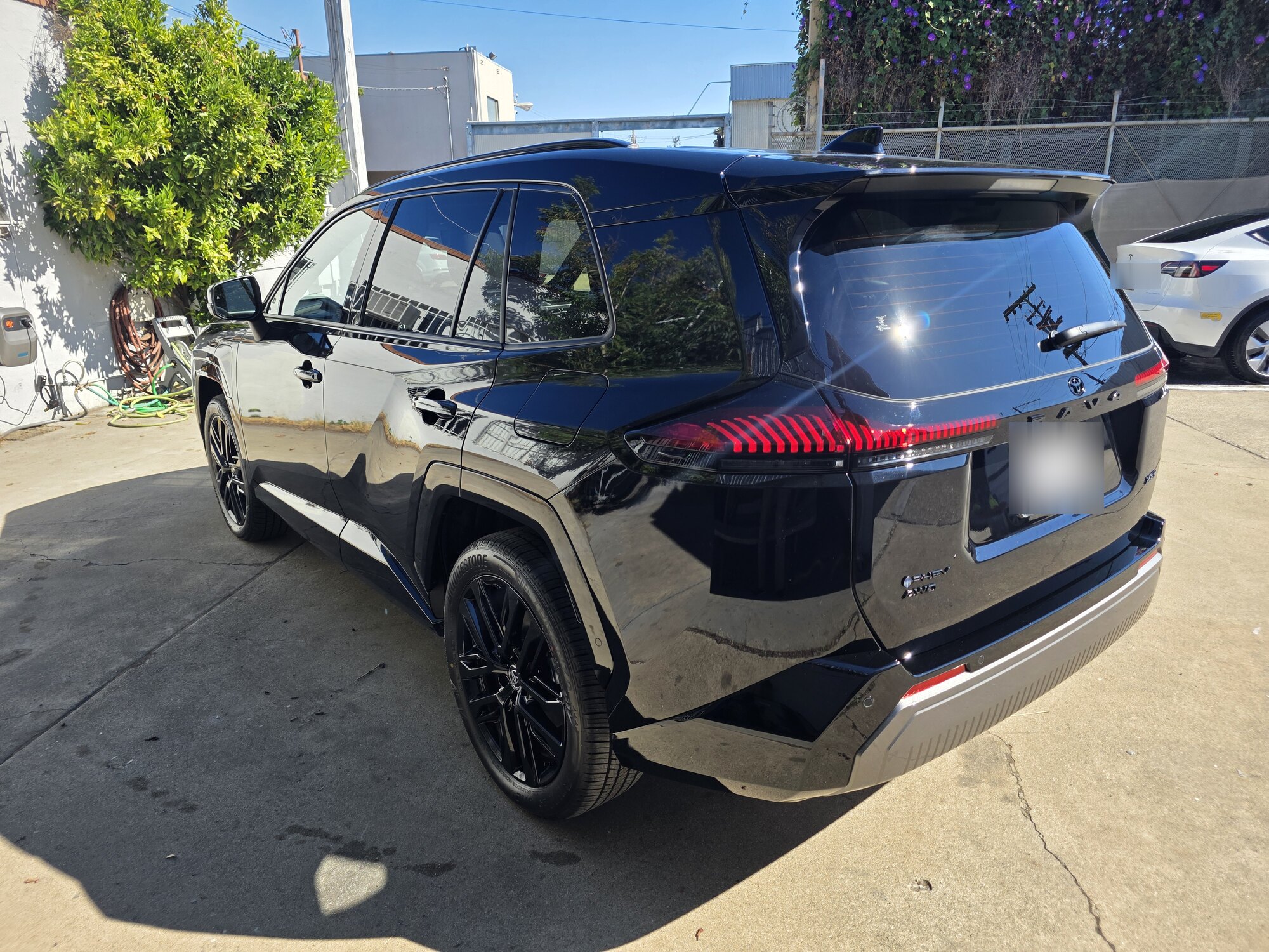 Rear three-quarter view of a dark blue 2026 Toyota RAV4 after a ceramic coating, the liftgate and quarter panel reflecting the sky.