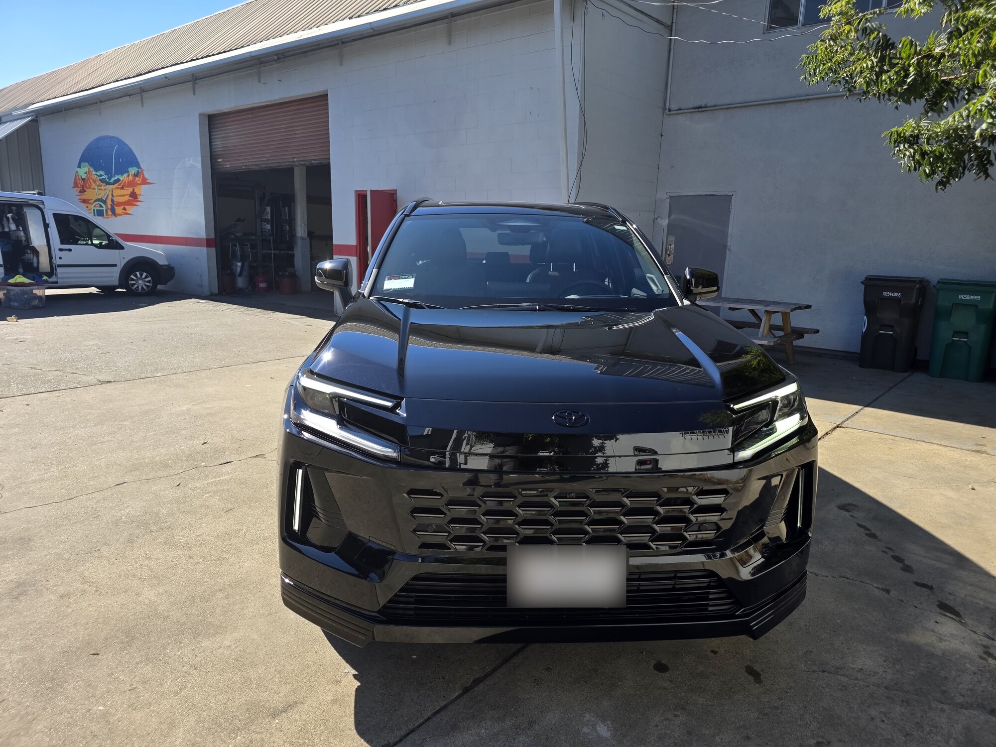 Straight-on front view of a dark blue 2026 Toyota RAV4 with clear paint protection film on the hood, bumper and headlights, outside the Innovo shop in Oakland.