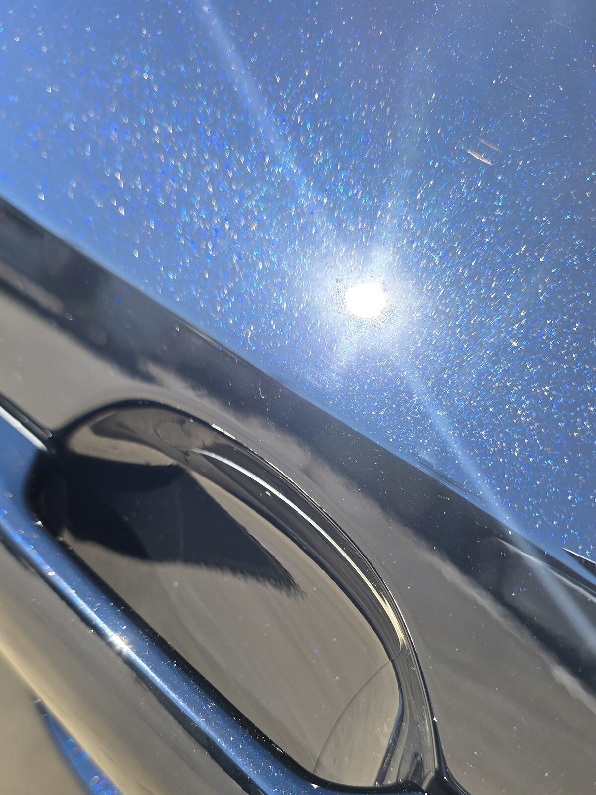 Door handle cup on a dark blue 2026 Toyota RAV4 with a clear paint protection film patch, the film edge following the handle recess.